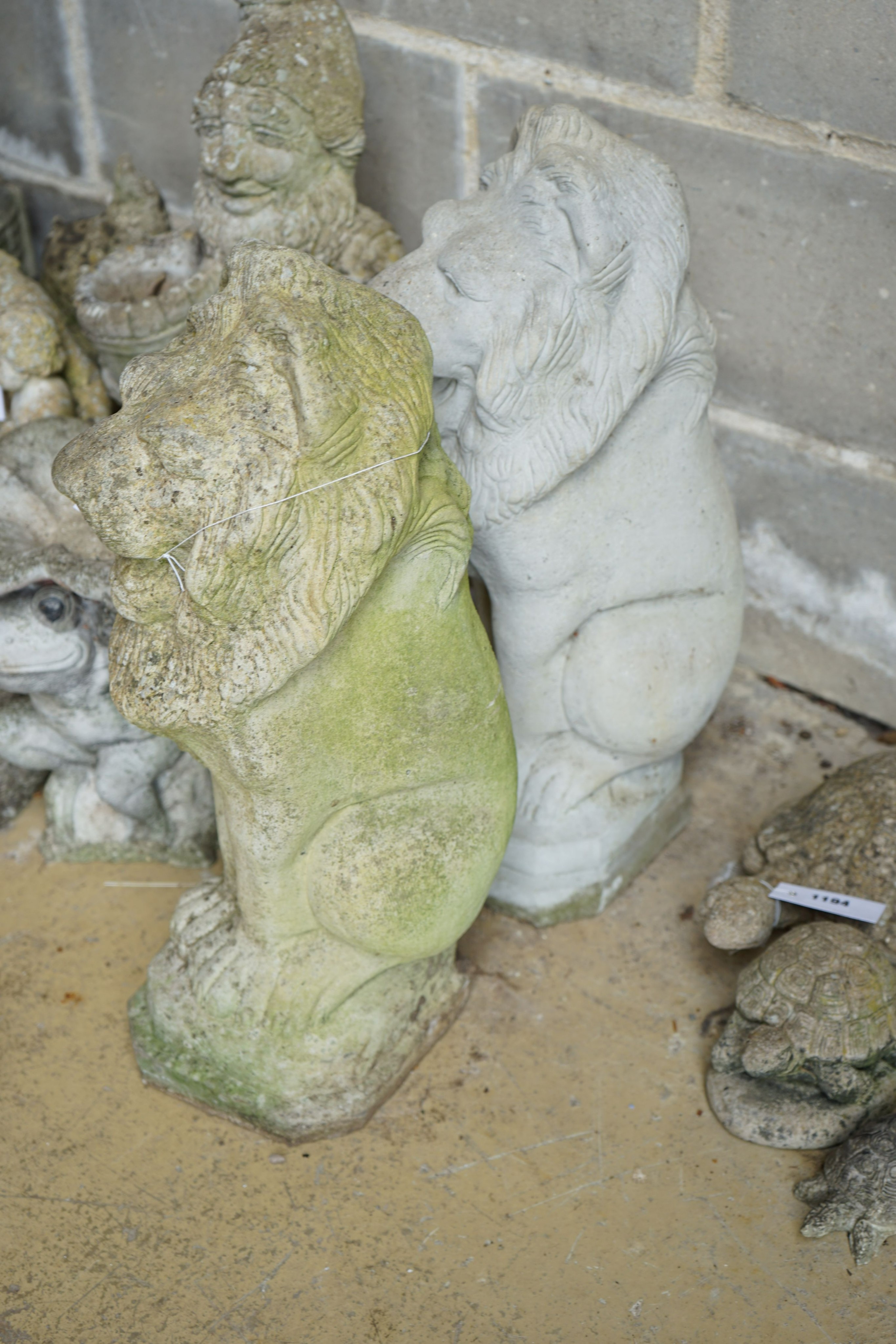 A pair of reconstituted stone seated lion garden ornaments, height 56cm